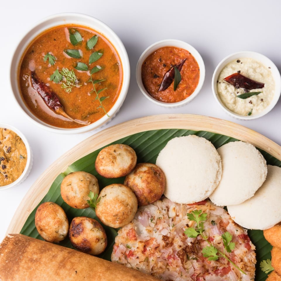 Aha South Indian Cuisine platter with dosa, idli, vada, sambar, and chutneys on a banana leaf.
