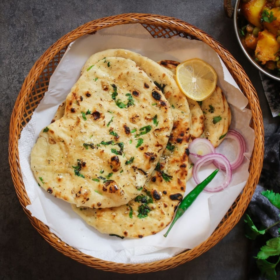 Aha South Indian Cuisine's naan bread in a basket with lemon, onions, and green chili.