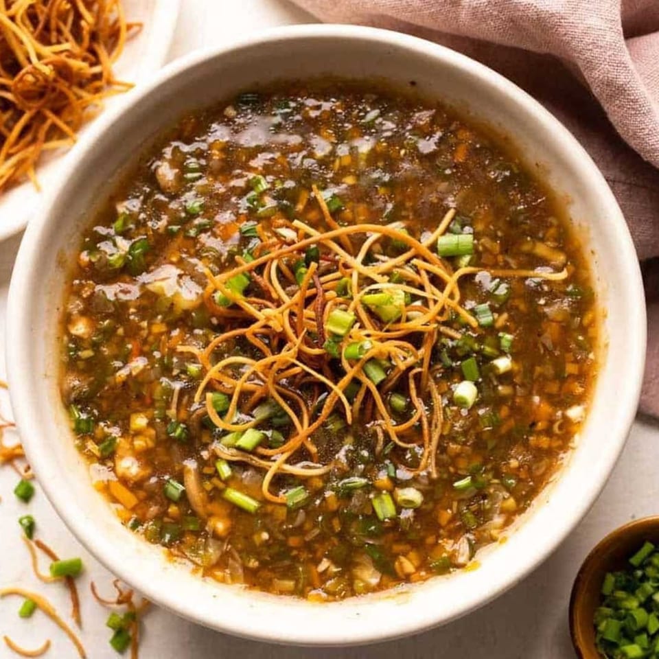 Aha South Indian Cuisine's hot and sour soup, garnished with crispy noodles and green onions.